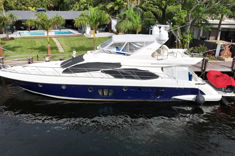 The Image of 2008 Azimut 62E yacht docked by a luxurious waterfront property with palm trees. - 0