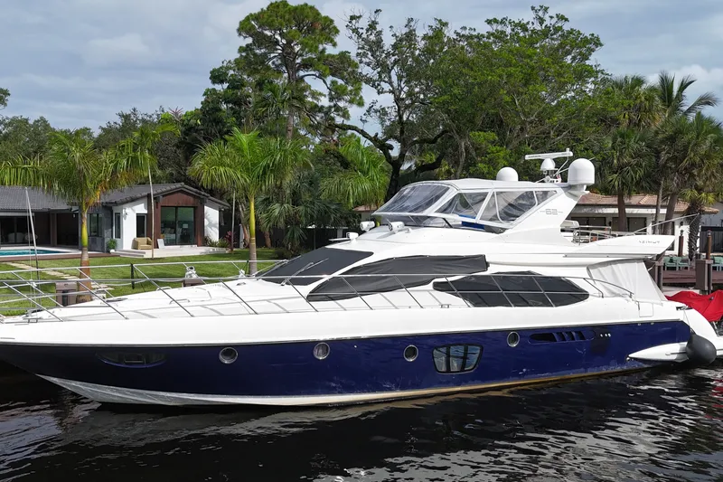 Slide: The Image of 2008 Azimut 62E yacht docked by lush waterfront property with palm trees. - 1
