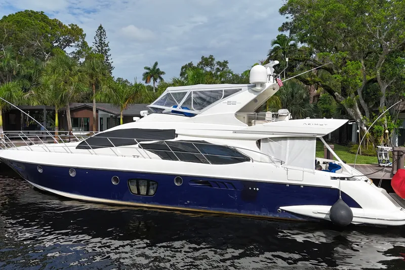 Slide: The Image of Luxury 2008 Azimut 62E yacht docked by lush greenery and calm waters. - 2