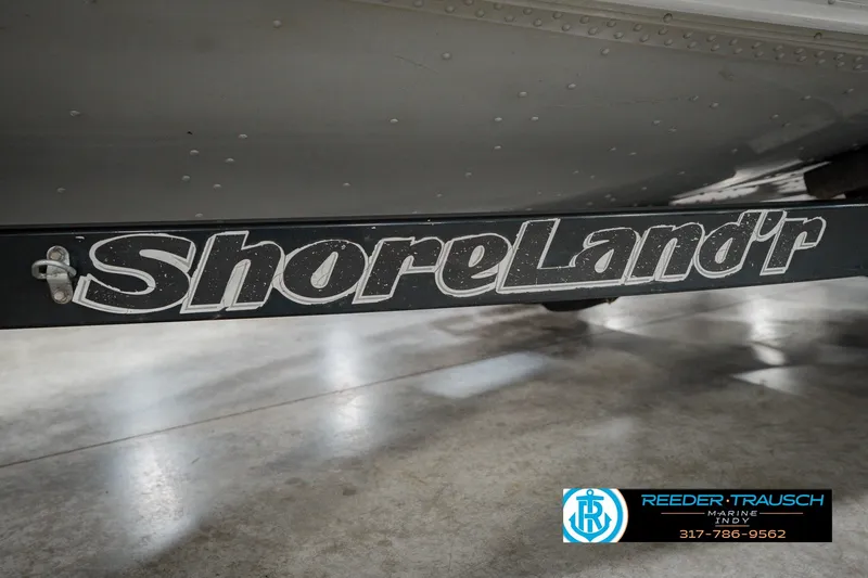 Slide: The Image of 1999 Lund Mr. Pike 17 boat trailer with ShoreLand'r branding in a showroom. - 60