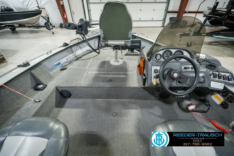 Slide: The Image of 1999 Lund Mr. Pike 17 boat interior with steering console and seating in a showroom. - 18