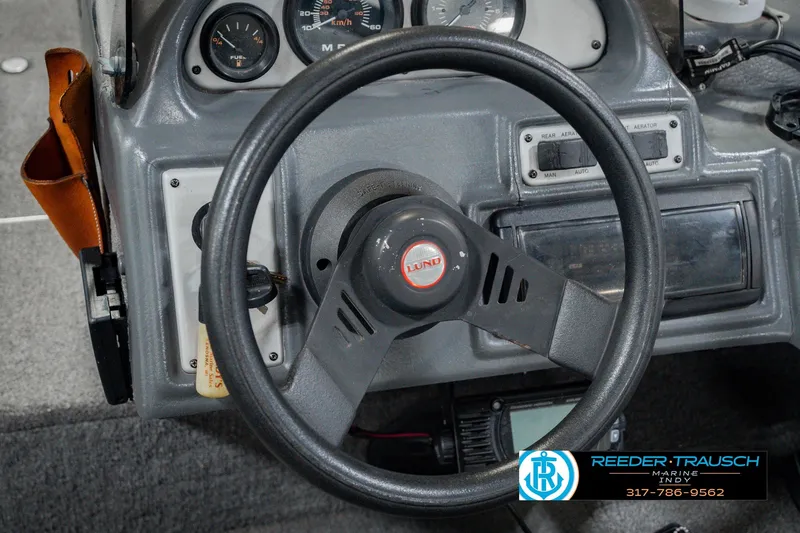 Slide: The Image of Dashboard of a 1999 Lund Mr. Pike 17 boat with steering wheel and gauges. - 33