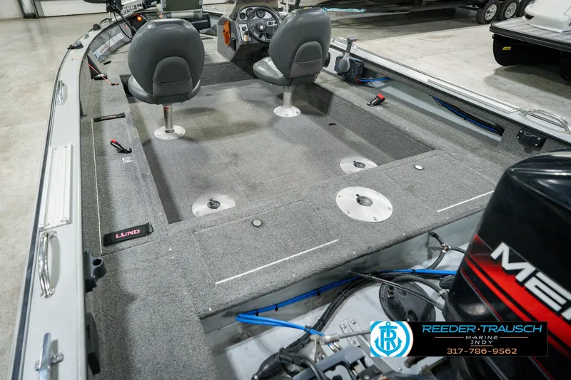Slide: The Image of 1999 Lund Mr. Pike 17 boat interior with seating and motor, displayed indoors. - 16
