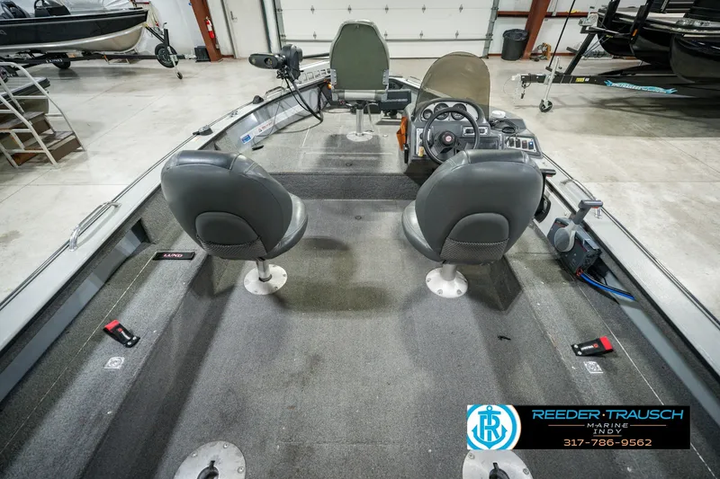 Slide: The Image of 1999 Lund Mr. Pike 17 boat interior with dual seats and steering console in a showroom. - 17
