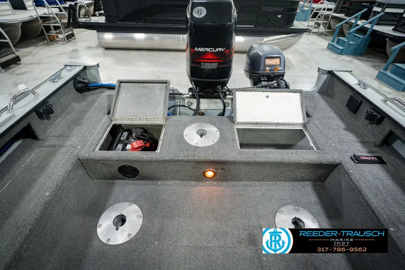 Slide: The Image of 1999 Lund Mr. Pike 17 boat interior with Mercury 125 engine, storage compartments, and carpeted flooring. - 25
