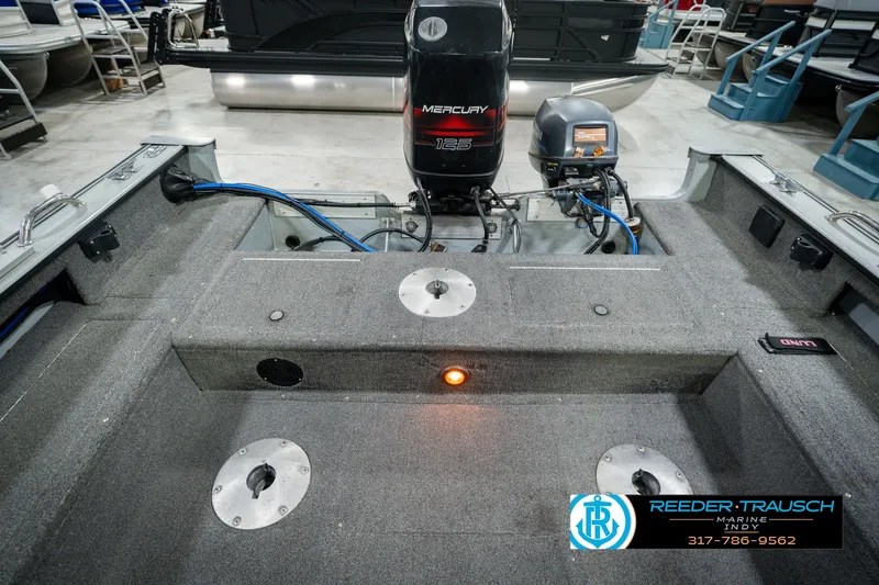 Slide: The Image of 1999 Lund Mr. Pike 17 boat interior with Mercury engine, carpeted deck, and storage compartments. - 24
