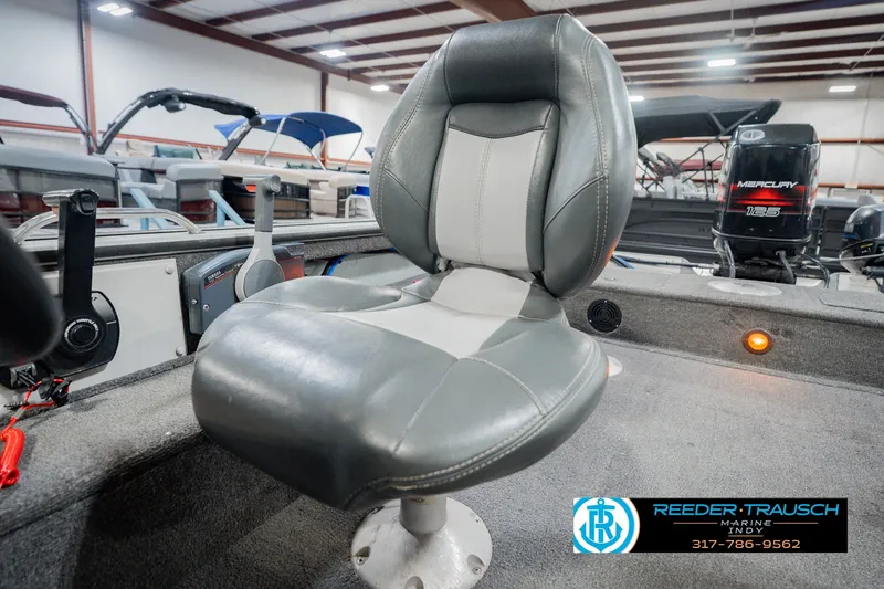 Slide: The Image of 1999 Lund Mr. Pike 17 boat interior with gray captain's chair and Mercury engine in showroom. - 40