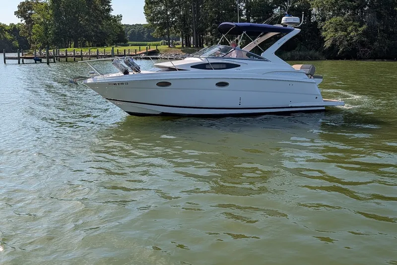 The Image of 2015 Regal 30 Express boat cruising on a calm lake with lush greenery. - 0