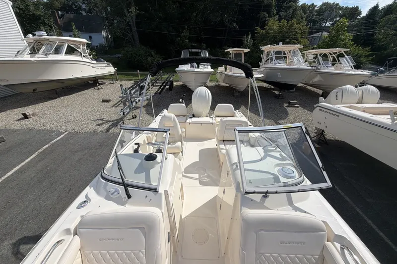 Slide: The Image of The image shows a 2027 Grady-White Freedom 215 boat parked on a gravel lot with other boats. - 11
