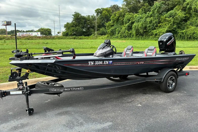 The Image of 2023 Ranger RT178 boat on trailer, parked outdoors with lush greenery background. - 1