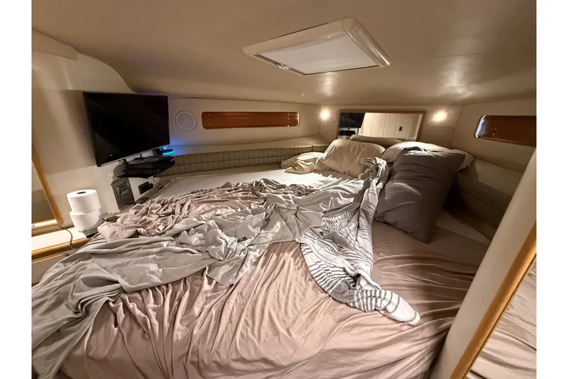 Slide: The Image of Cozy cabin interior of 1994 Sea Ray 500 Sundancer with unmade bed and TV. - 43