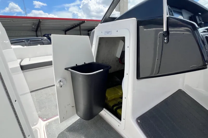 Slide: The Image of 2022 Yamaha AR190 boat storage compartment with open door and trash bin. - 35
