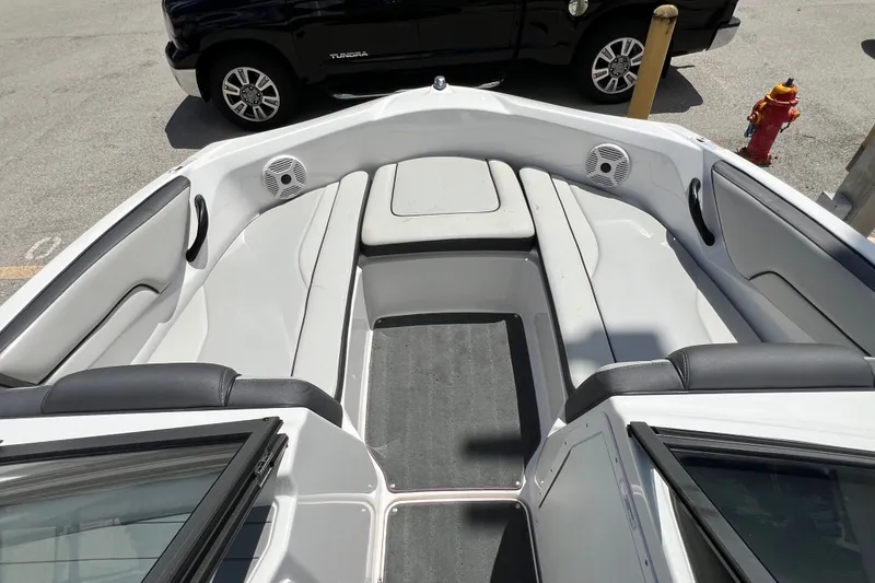 Slide: The Image of 2022 Yamaha Boats AR190 interior with seating and speakers, parked near a black vehicle. - 19