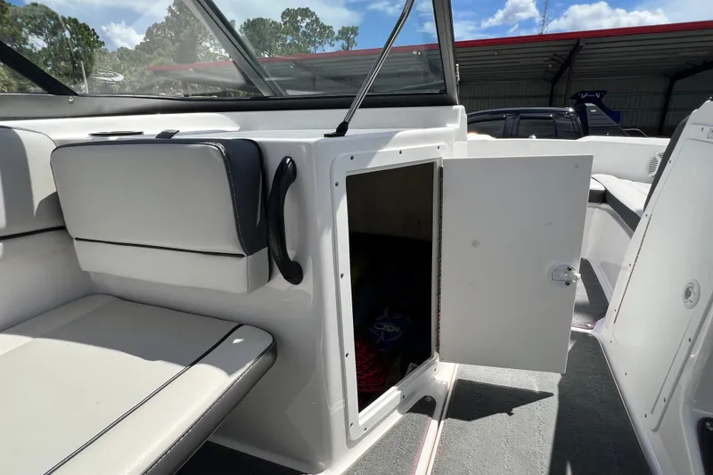 Slide: The Image of 2022 Yamaha Boats AR190 interior storage compartment with open door, showcasing seating area. - 33