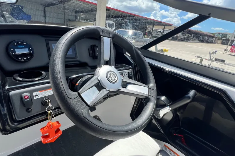 Slide: The Image of 2022 Yamaha Boats AR190 steering wheel and dashboard in a marina setting. - 37
