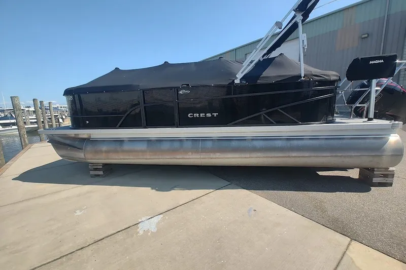 Slide: The Image of 2024 Crest 220SLC Classic LX pontoon boat docked, covered with a black canopy. - 5