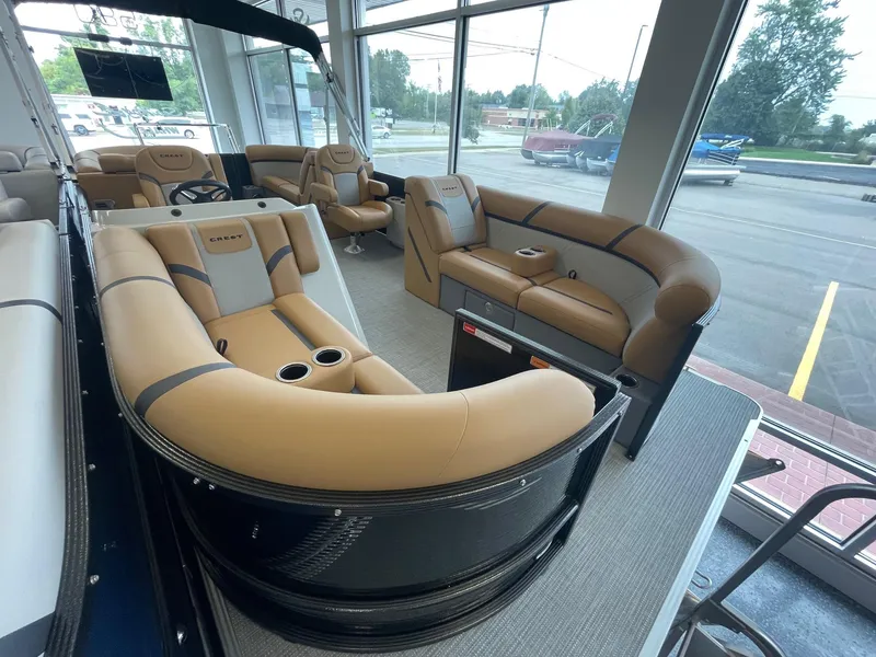 Slide: The Image of 2024 Crest 220SLC Classic LX pontoon boat with luxurious tan seating in showroom. - 9