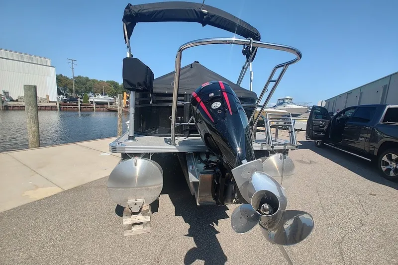 Slide: The Image of 2024 Crest 220SLC Classic LX pontoon boat with outboard motor, docked near water. - 2