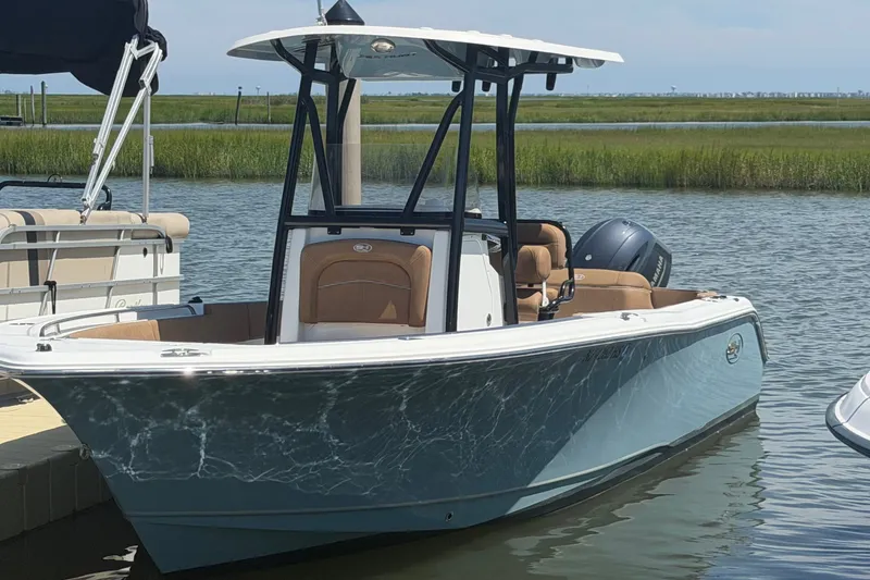 The Image of 2023 Sea Hunt Ultra 234 boat docked on calm water, showcasing sleek design and modern features. - 0