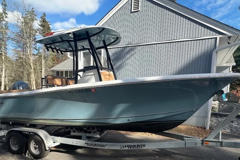 Slide: The Image of 2023 Sea Hunt Ultra 234 boat on trailer, parked near a house, under clear sky. - 15