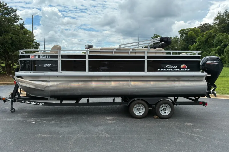 The Image of 2025 Sun Tracker SportFish 20 DLX pontoon boat on trailer, parked outdoors. - 1