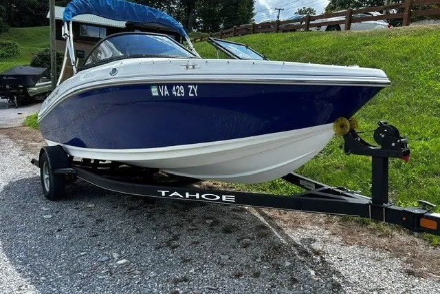 Slide: The Image of 2021 Tahoe 450 TS boat on trailer, parked on gravel near grassy hill. - 5