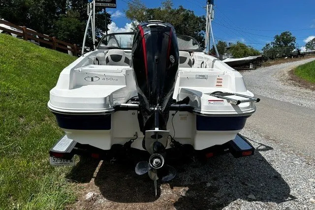 Slide: The Image of 2021 Tahoe 450 TS boat, rear view, parked on a gravel path under a clear blue sky. - 7