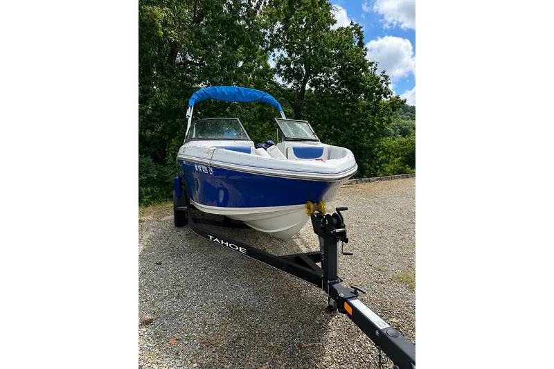 Slide: The Image of 2021 Tahoe 450 TS boat on trailer, blue and white, parked outdoors. - 2