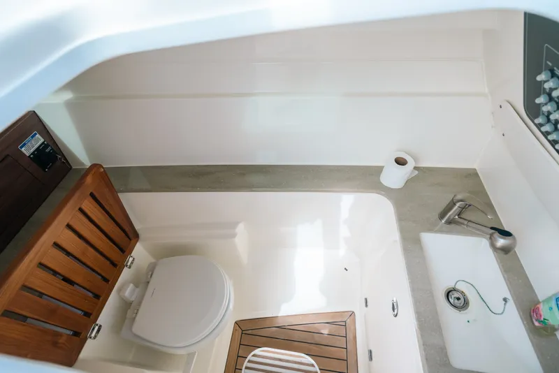 Slide: The Image of 2024 Boston Whaler 320 Vantage boat bathroom with toilet, sink, and wooden accents. - 46