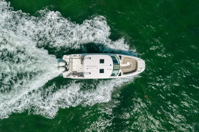 Slide: The Image of Aerial view of 2024 Boston Whaler 320 Vantage cruising through vibrant green waters. - 13