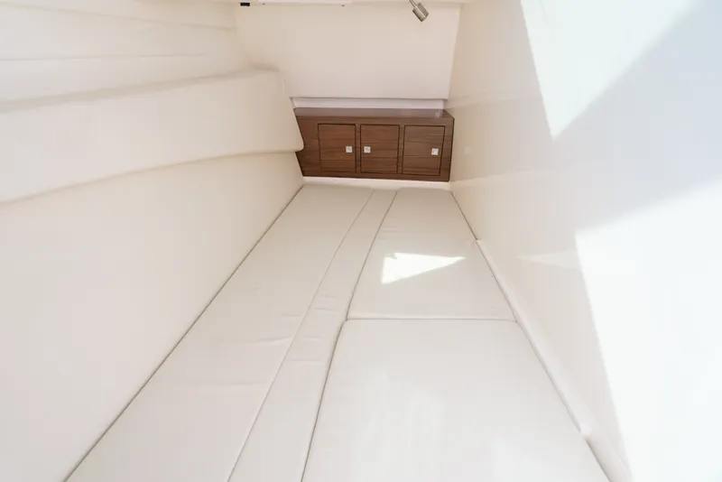 Slide: The Image of 2024 Boston Whaler 320 Vantage cabin interior with cushioned seating and wooden storage cabinets. - 62