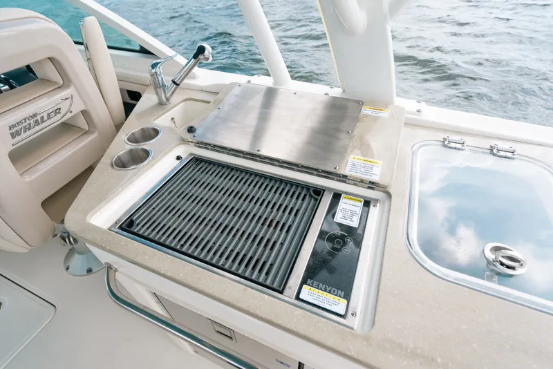 Slide: The Image of 2024 Boston Whaler 320 Vantage boat grill and sink area with ocean backdrop. - 32