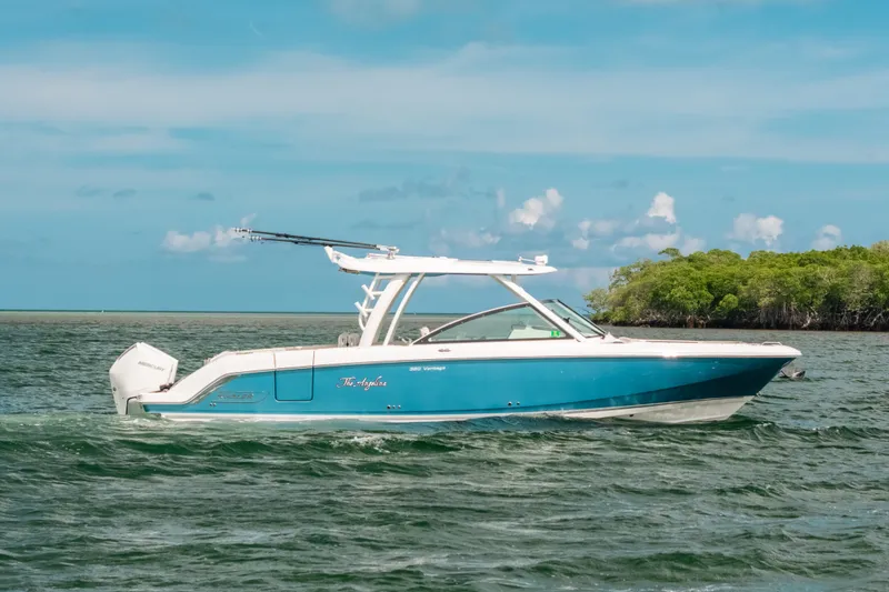 Slide: The Image of 2024 Boston Whaler 320 Vantage boat cruising on a sunny day near lush green shoreline. - 7