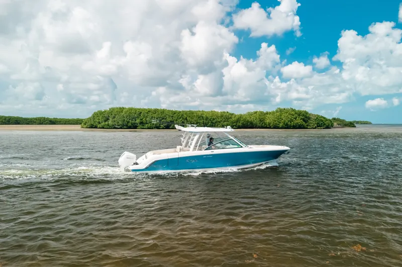Slide: The Image of 2024 Boston Whaler 320 Vantage cruising on a scenic waterway under a bright blue sky. - 22