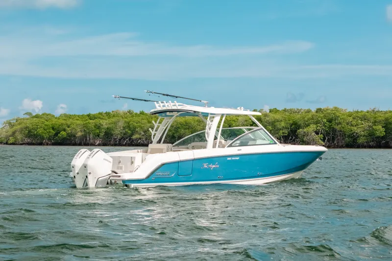 Slide: The Image of 2024 Boston Whaler 320 Vantage boat cruising on a scenic waterway with lush greenery. - 6