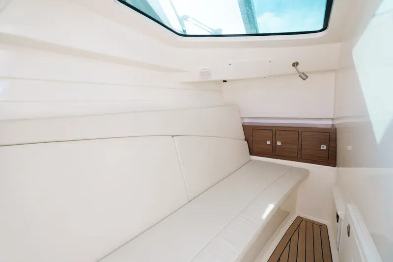Slide: The Image of Interior cabin of 2024 Boston Whaler 320 Vantage, featuring sleek seating and wooden storage cabinets. - 57