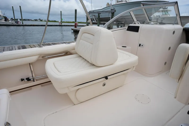 Slide: The Image of 2022 Grady-White Freedom 215 boat interior with cushioned seating and sleek design at a marina. - 17