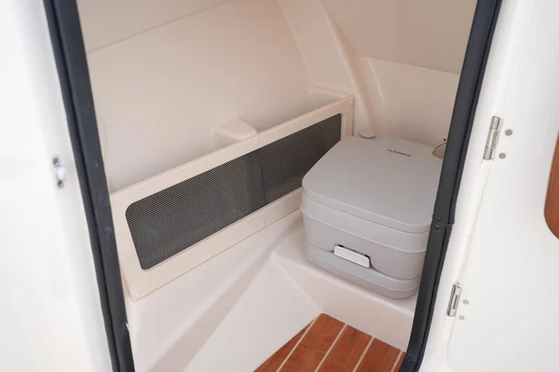 Slide: The Image of 2022 Grady-White Freedom 215 boat interior with portable toilet and wooden flooring. - 26