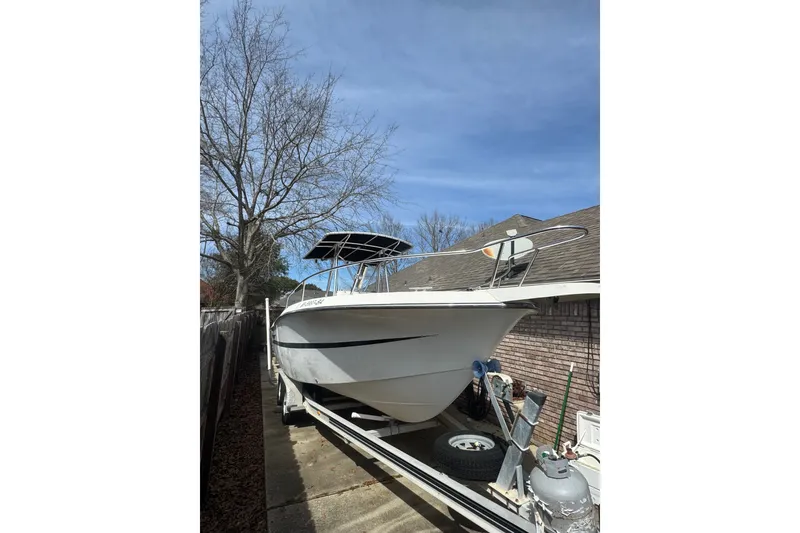 Slide: The Image of 1993 Hydra-Sports 2300 CC boat on trailer, parked beside a brick house under clear blue sky. - 14