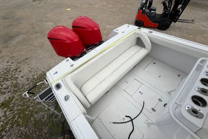 Slide: The Image of 2000 Intrepid 322 boat with red dual engines and white seating, parked near a forklift. - 14