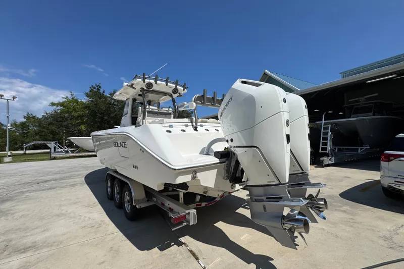 Slide: The Image of 2027 Solace 32CS boat with dual Mercury engines on a trailer, parked outdoors. - 17