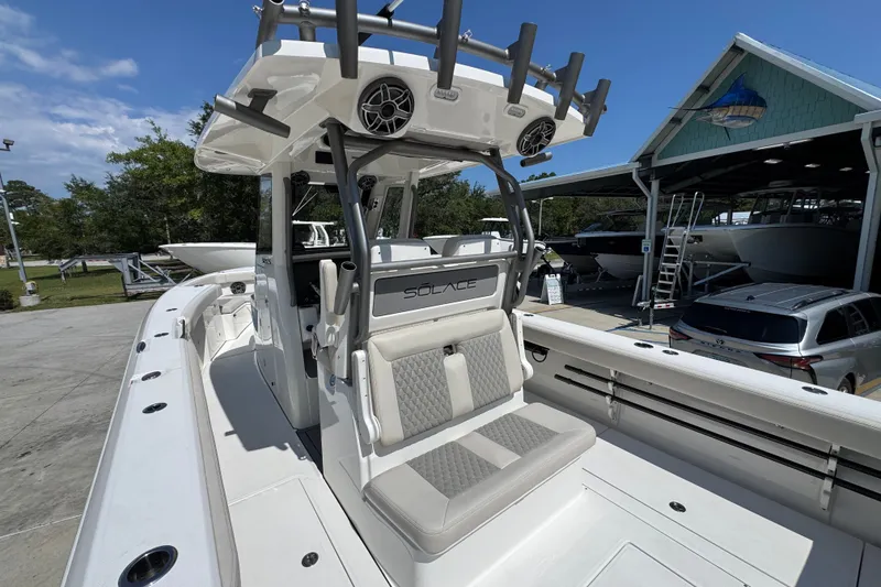 Slide: The Image of 2027 Solace 32CS boat with seating and rod holders, docked near a boathouse. - 42