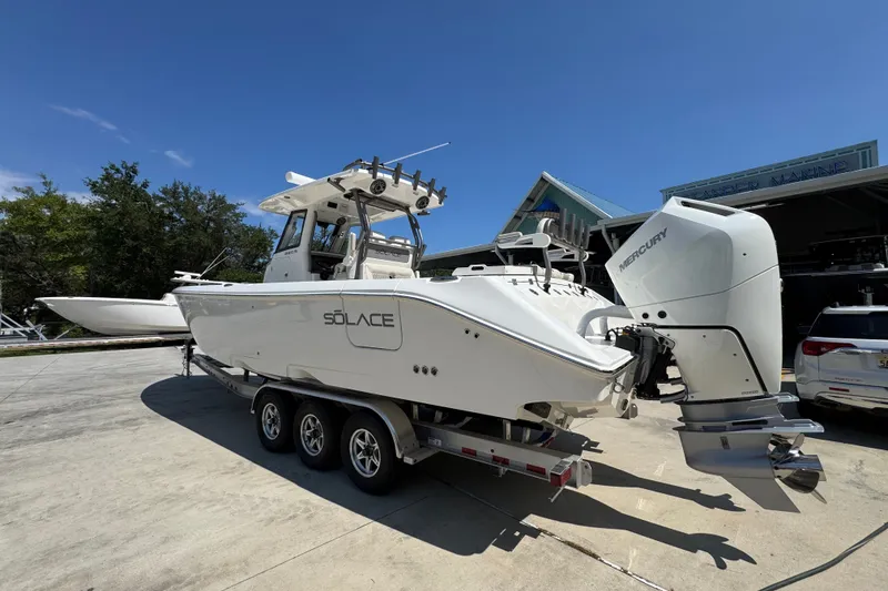 Slide: The Image of 2027 Solace 32CS boat on trailer with Mercury outboard engines, parked outdoors. - 18