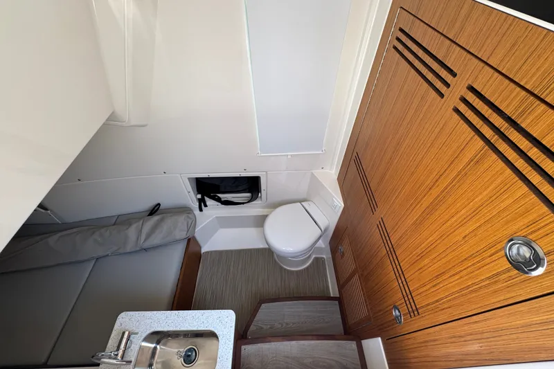 Slide: The Image of Interior of 2027 Solace 32CS boat featuring compact bathroom and wooden cabinetry. - 29