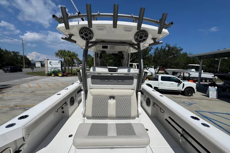 Slide: The Image of 2027 Solace 32CS boat interior with seating and rod holders, parked outdoors. - 43