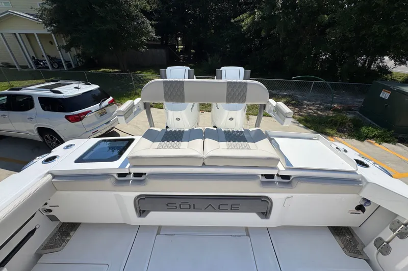 Slide: The Image of 2027 Solace 32CS boat with luxurious seating and sleek design in a parking area. - 51
