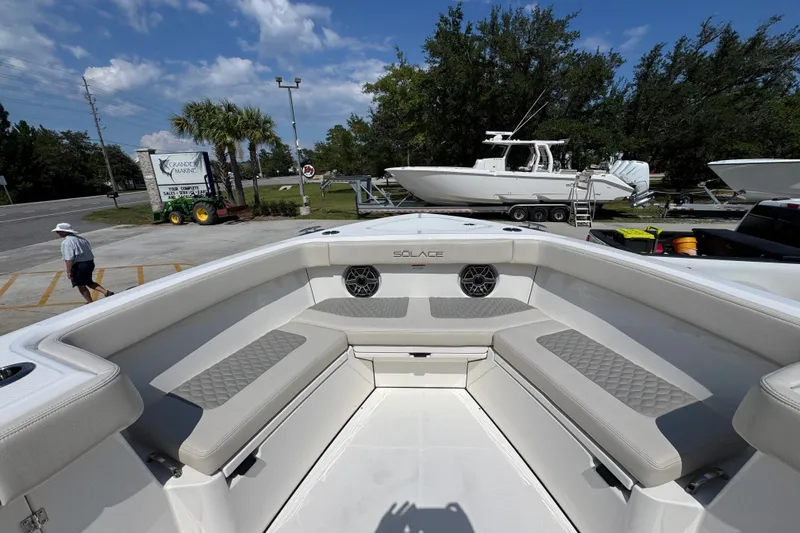 Slide: The Image of 2027 Solace 32CS boat interior with cushioned seating, parked at a marina under a clear sky. - 20