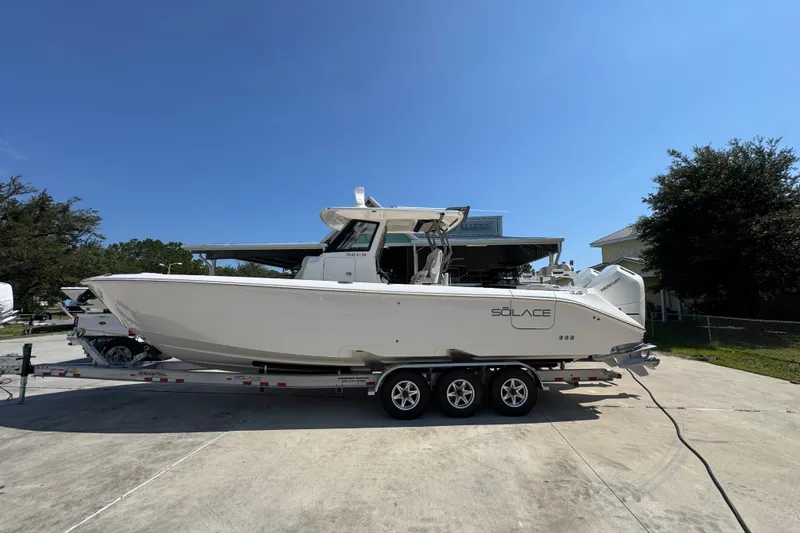 The Image of 2027 Solace 32CS boat on trailer under clear blue sky. - 1