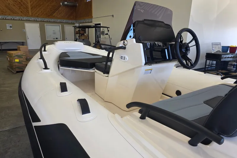 Slide: The Image of 2027 Grand Inflatables G420 boat interior with steering console and seating in a showroom. - 11