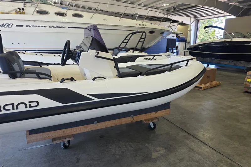 Slide: The Image of 2027 Grand Inflatables G420 boat displayed in a showroom with other vessels. - 7